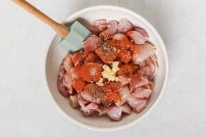 Mixing diced chicken thighs with seasonings.