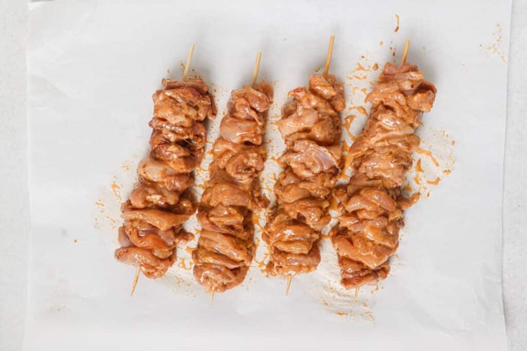 Seasoned chicken on wooden skewers.