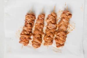 Seasoned chicken on wooden skewers.