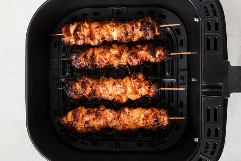 Bang bang chicken skewers in the air fryer basket.