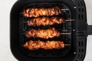 Bang bang chicken skewers in the air fryer basket.