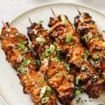 4 bang bang chicken skewers on a plate.