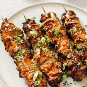 4 bang bang chicken skewers on a plate.