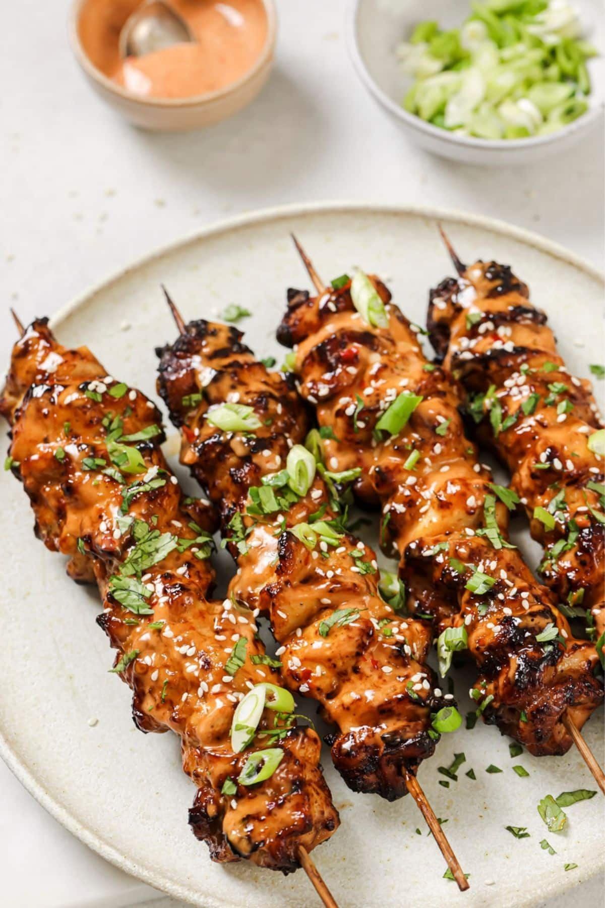 A plate of bang bang chicken on wooden skewers.