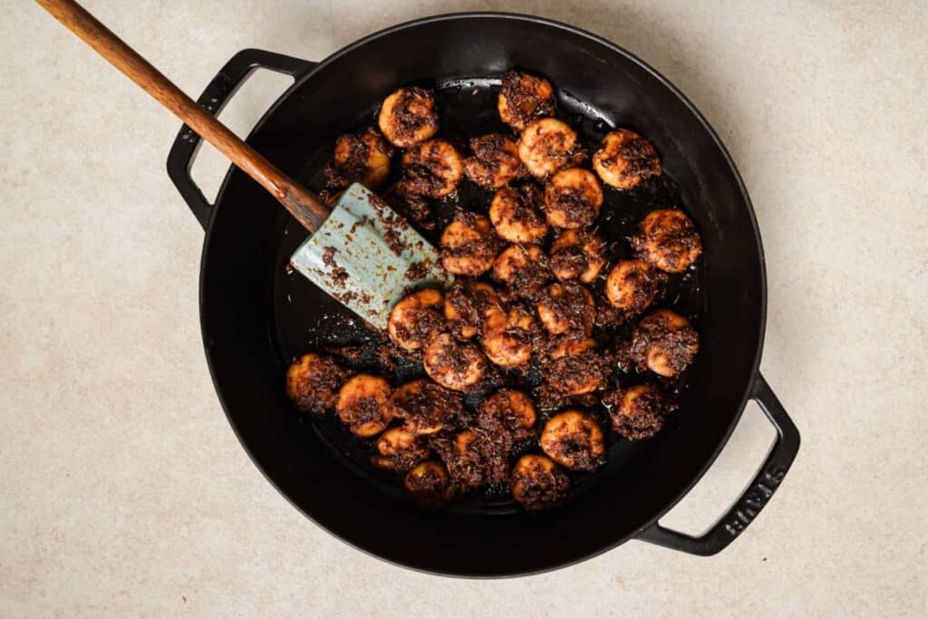 Cooking seasoned shrimp in a cast iron skillet.