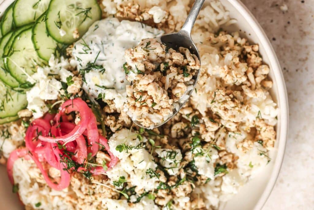 Close up of assembling a chicken and rice bowl.