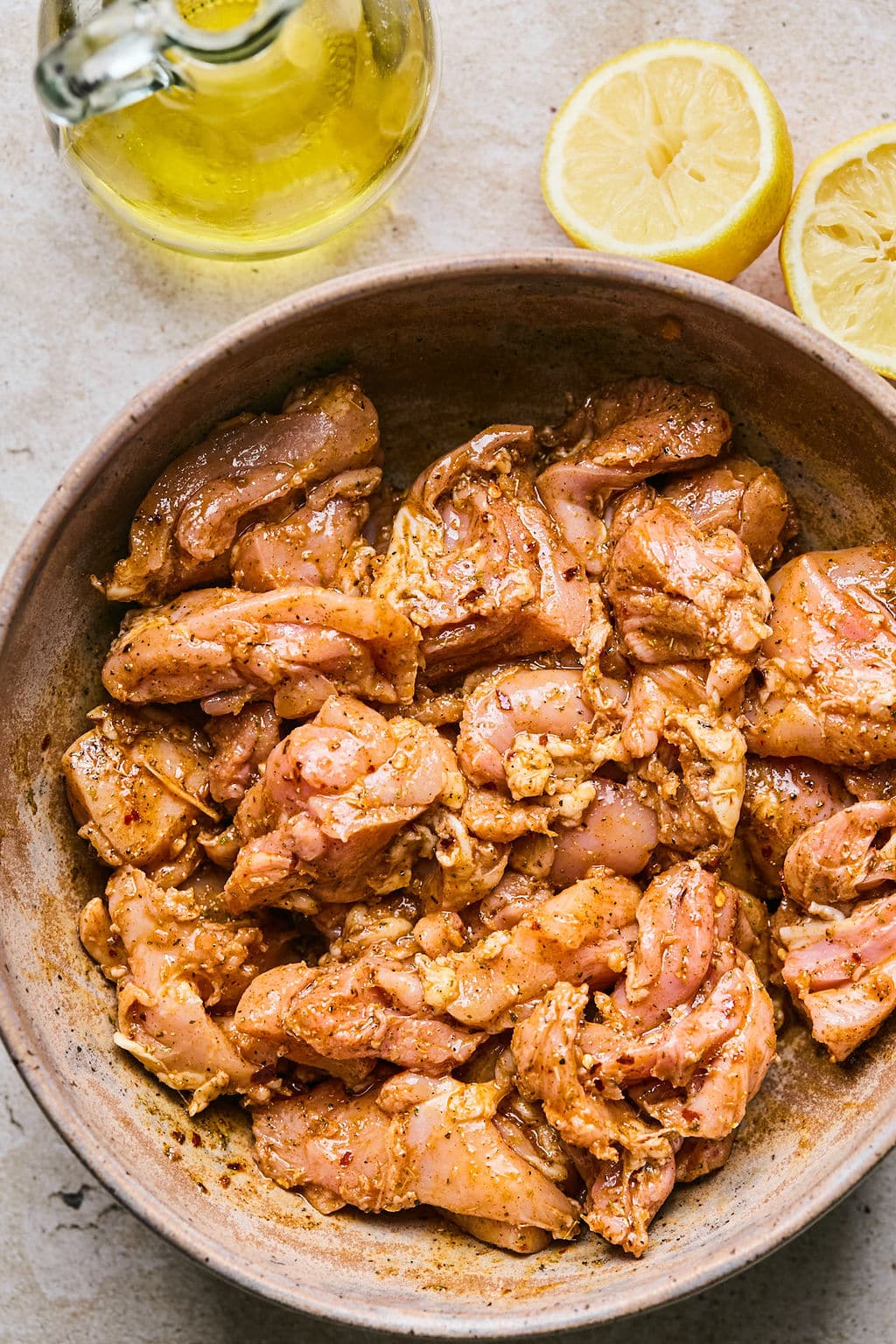Pieces of chicken thigh marinating in a bowl.