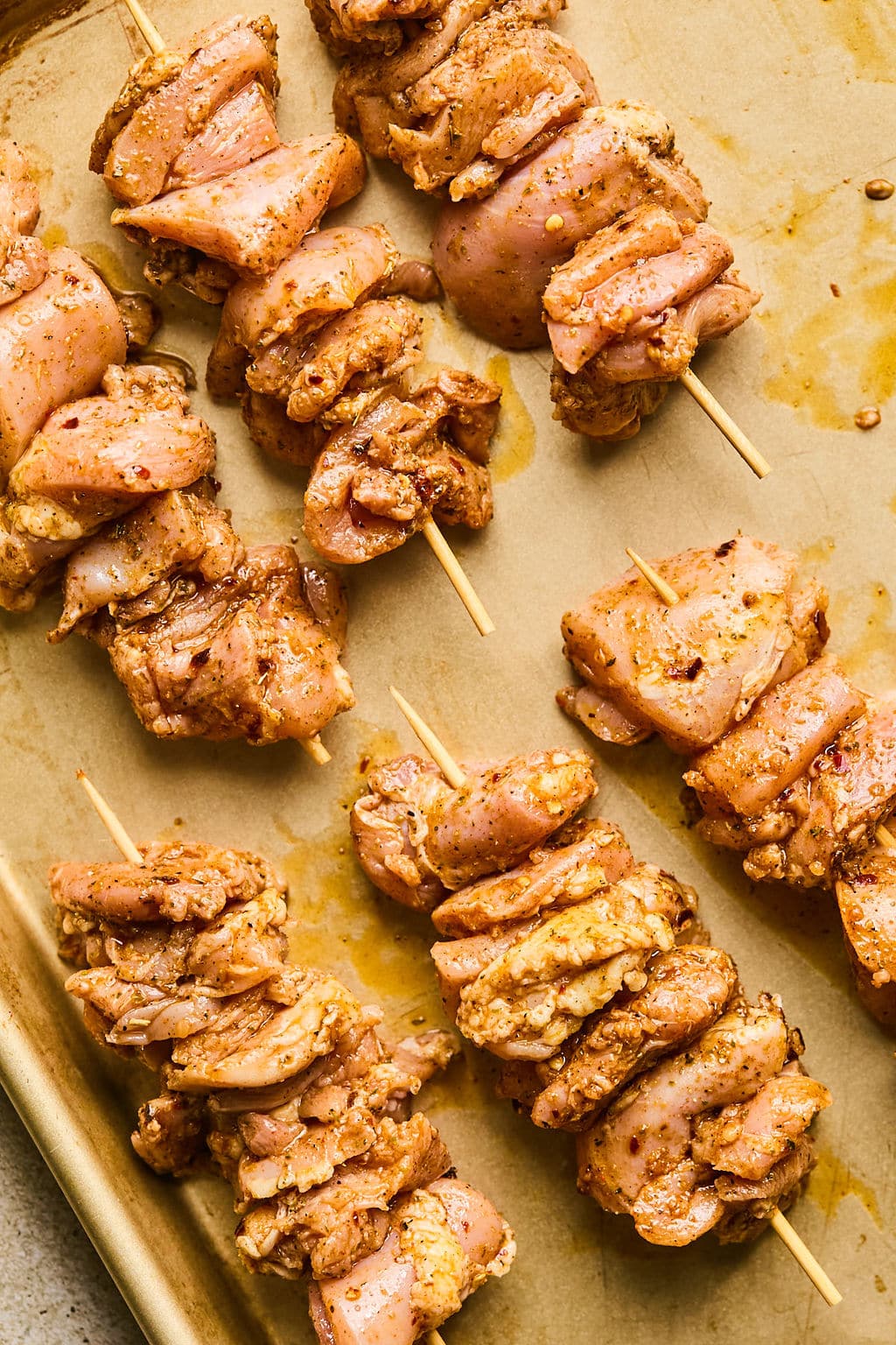 Marinated chicken thighs on wooden skewers.