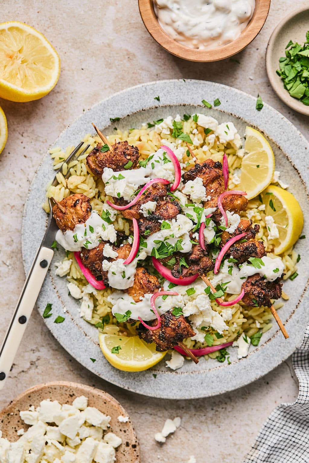 A plate of air fryer greek chicken skewers with lemon wedges and rice.