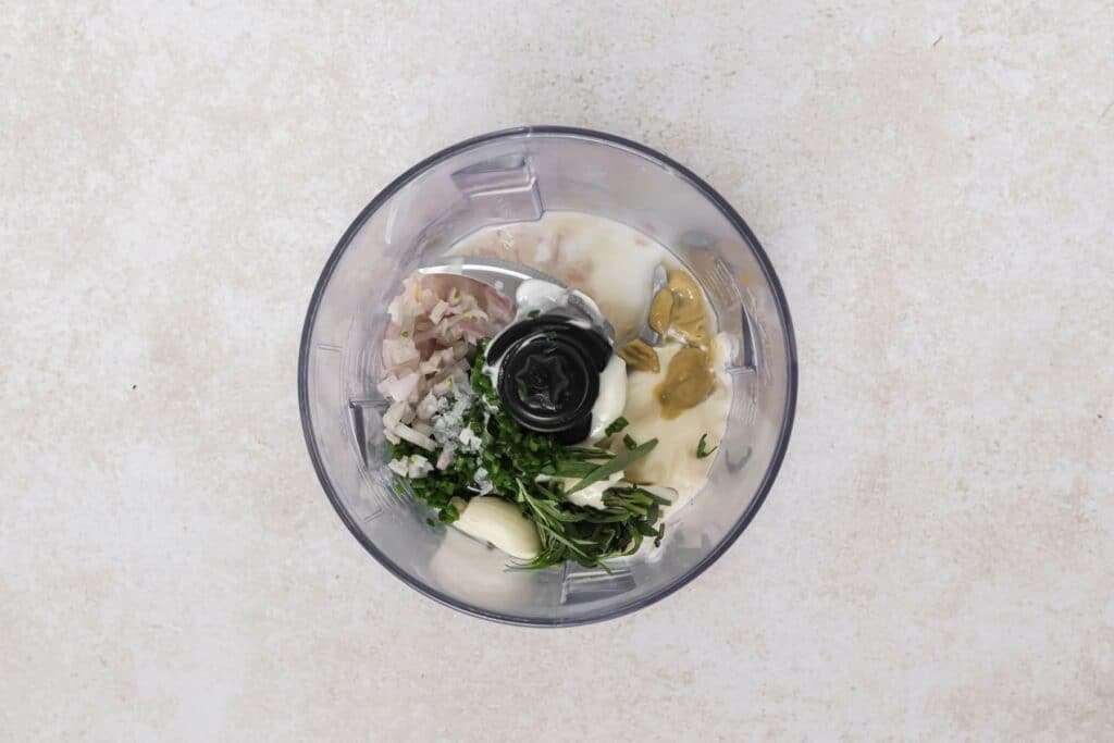 Warm potato salad dressing ingredients in a food processor.