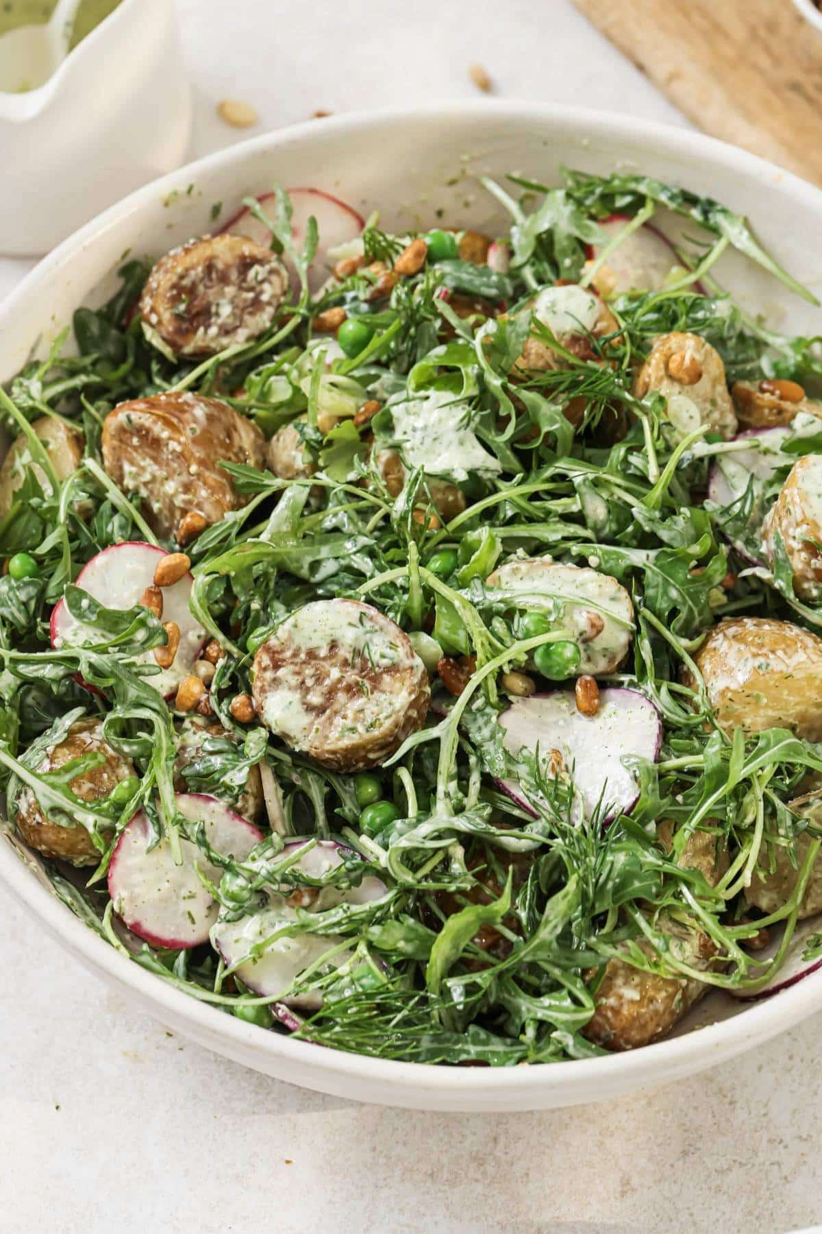 Warm potato salad in a white bowl.