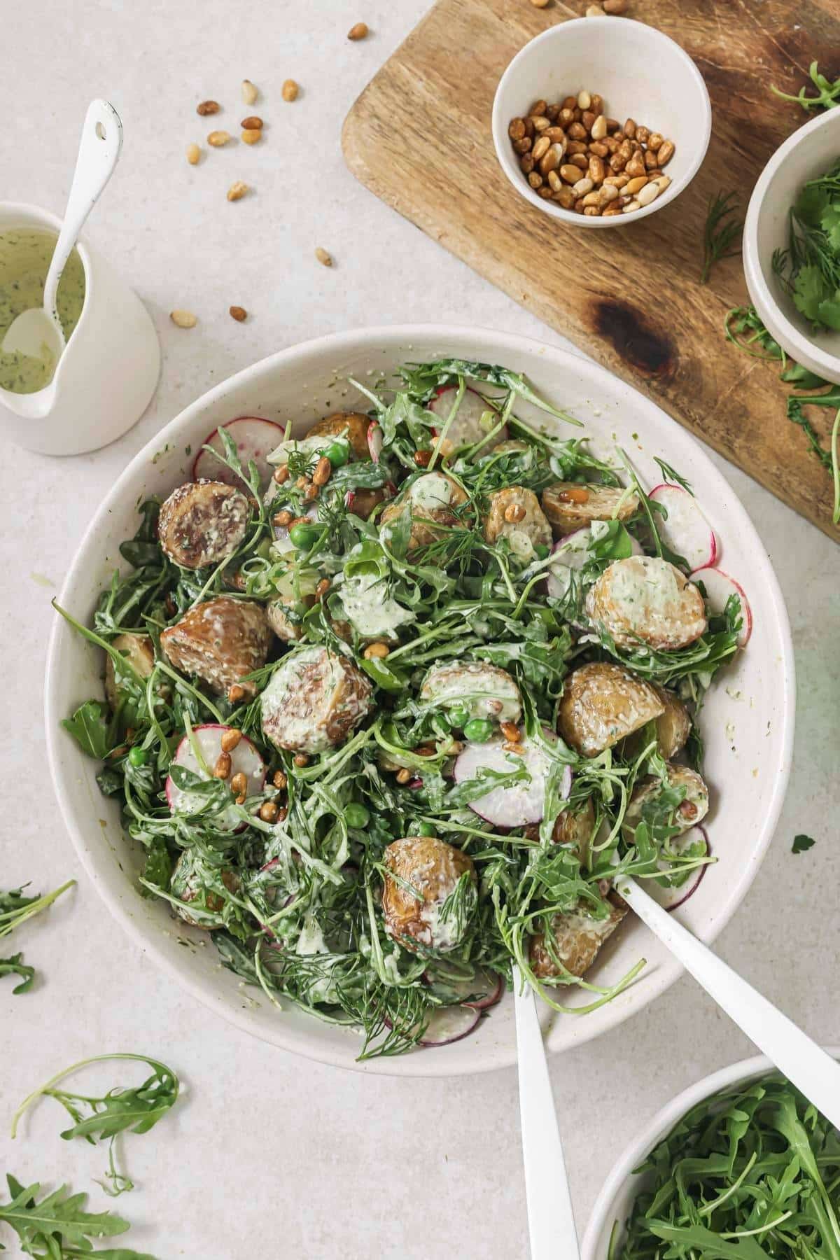 Roasted potato salad in a bowl surrounded by smaller bowls of toppings.