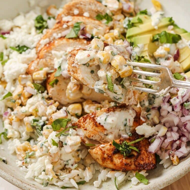 A fork picking up a bite of street corn chicken and rice.