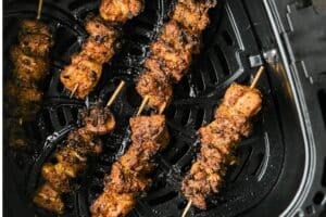 Cooked chicken skewers in an air fryer basket.