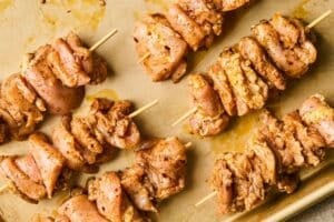 Marinated chicken thighs on wooden skewers.