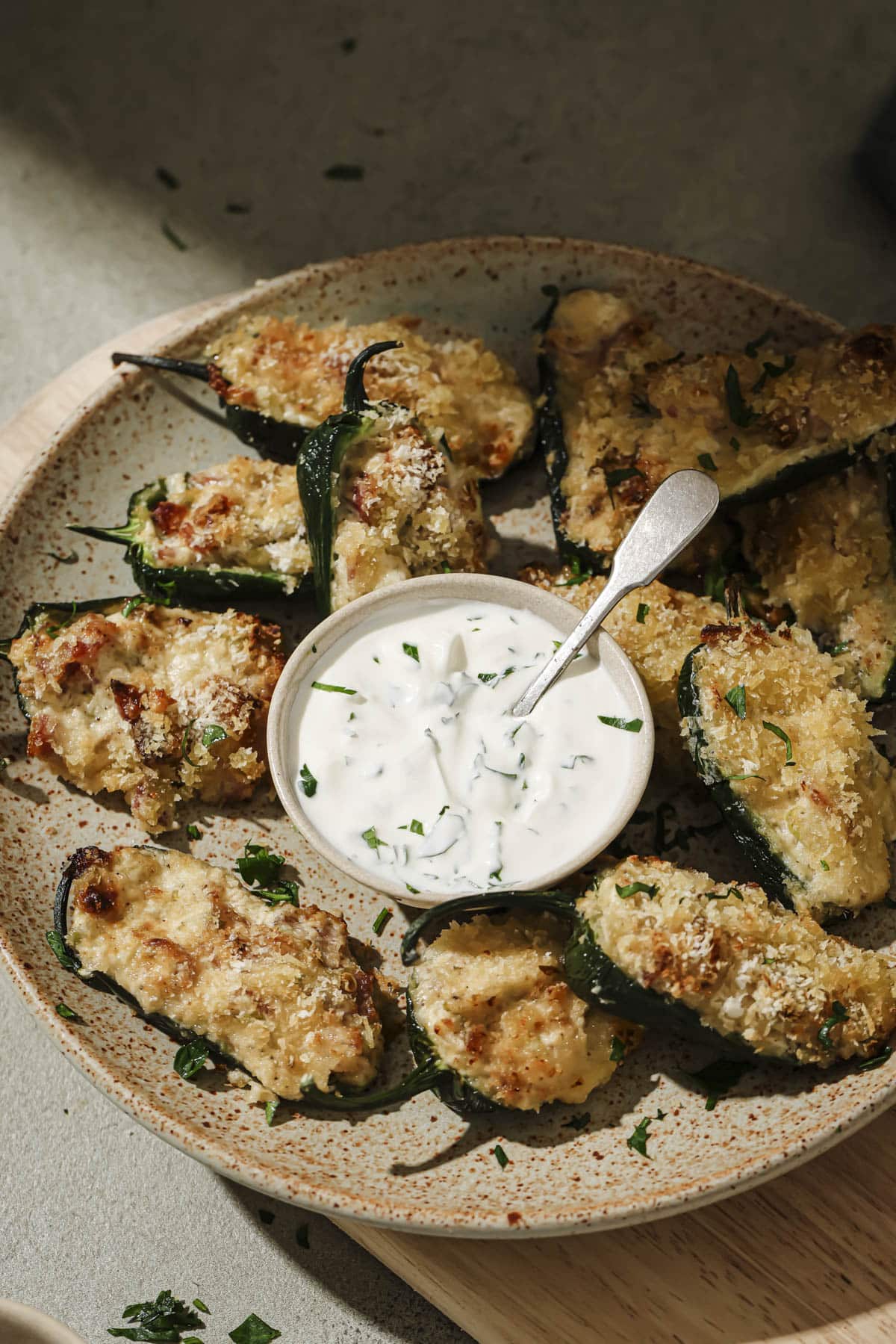 A plate of jalapeno poppers arranged around a small bowl of dipping sauce.
