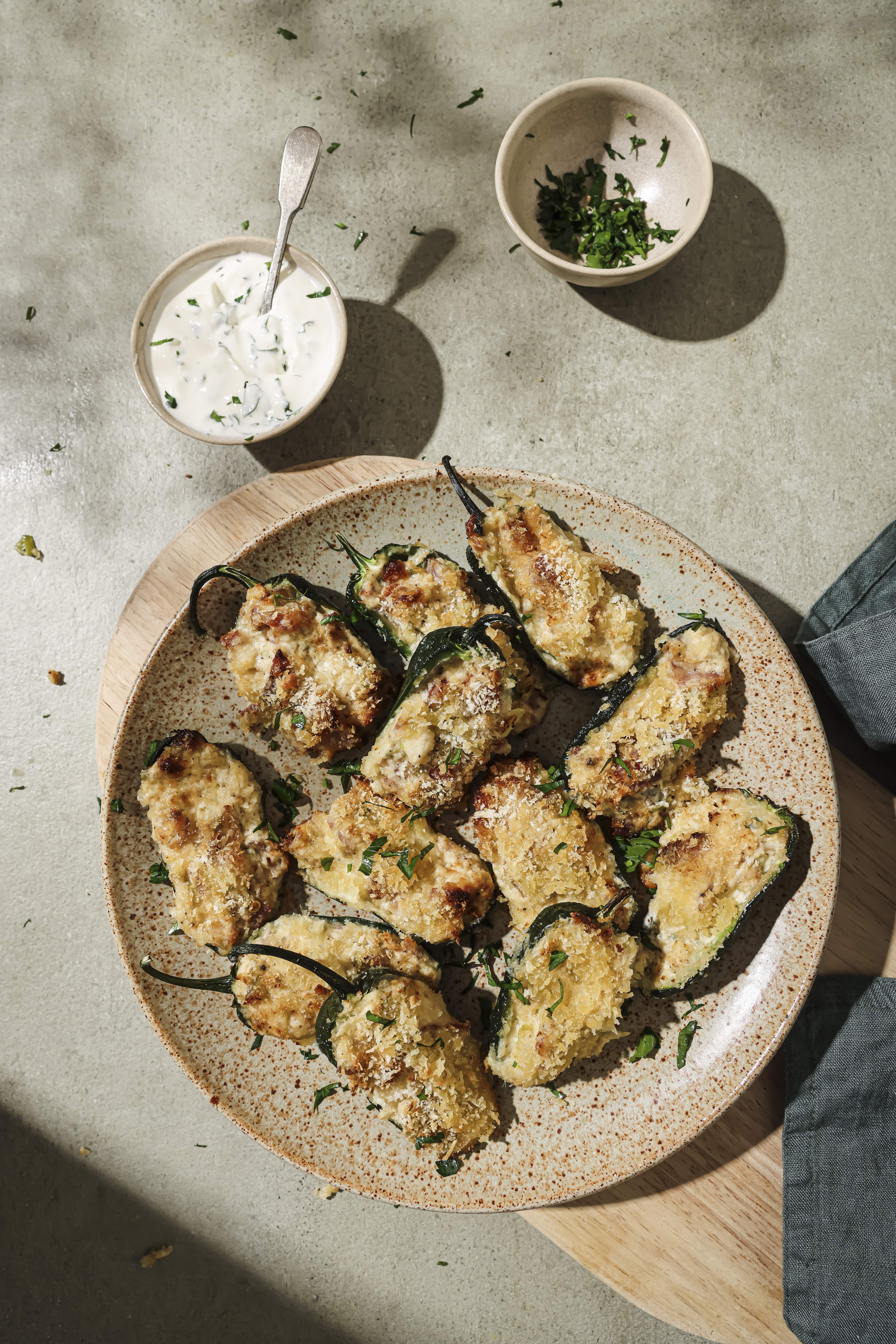 A plate of air fryer jalapeno poppers next to a small bowl of sauce.