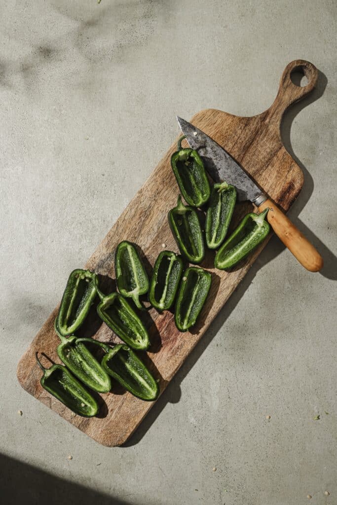 Hollowed out jalapenos on a cutting board.
