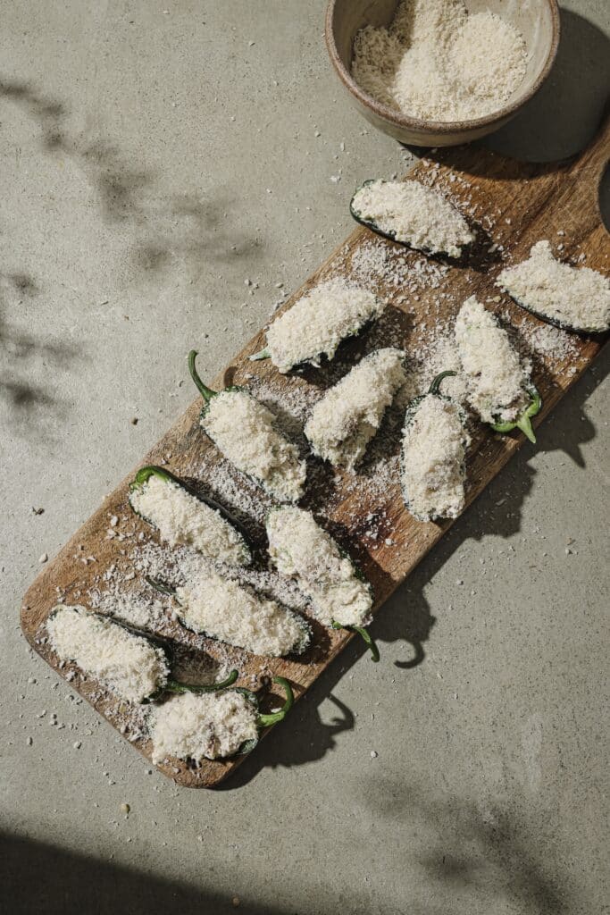 Uncooked prepared jalapeno poppers on a wooden cutting board.