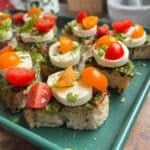 Tomato toast with mozzarella on a green sheet pan.
