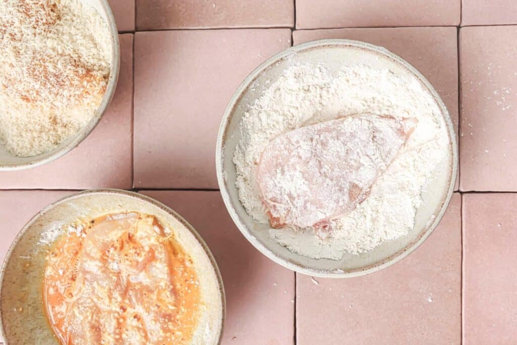 Dredging a chicken cutlet in flour.