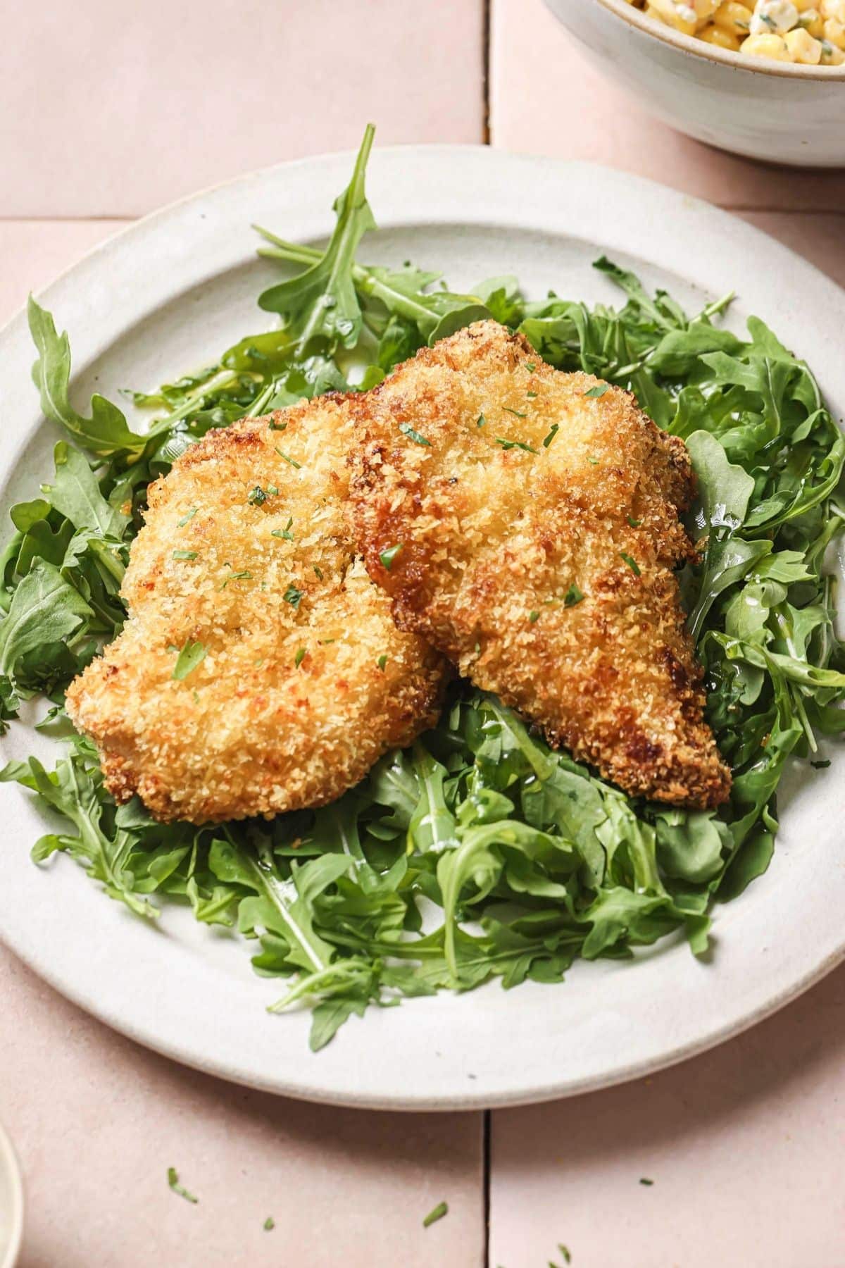 A plate of air fryer chicken cutlets served over greens.