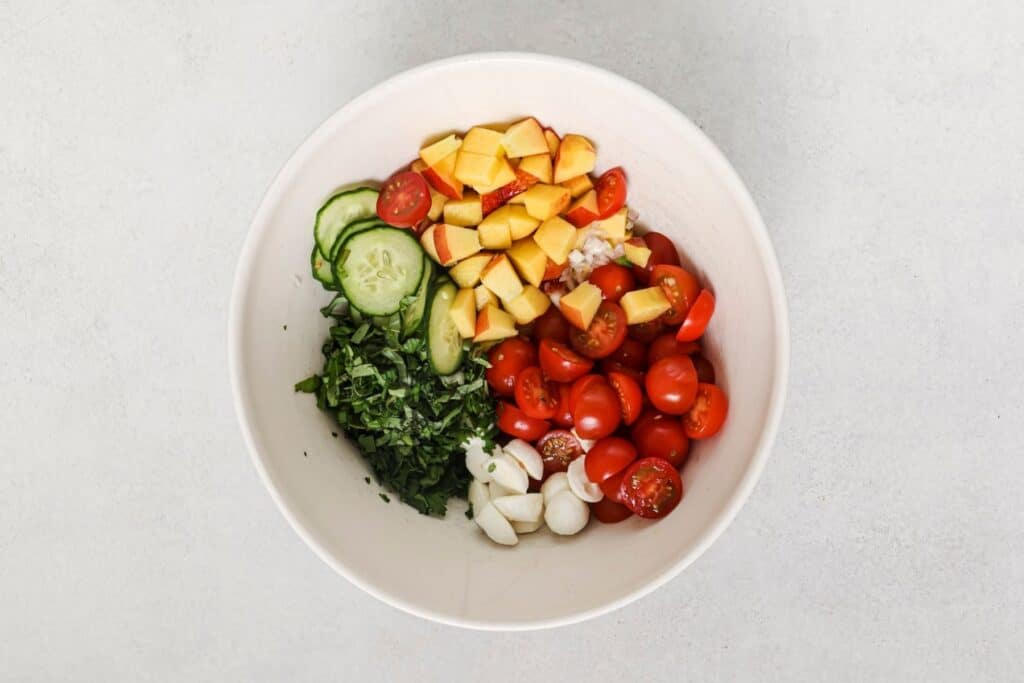 Produce for a tomato salad in a large bowl.