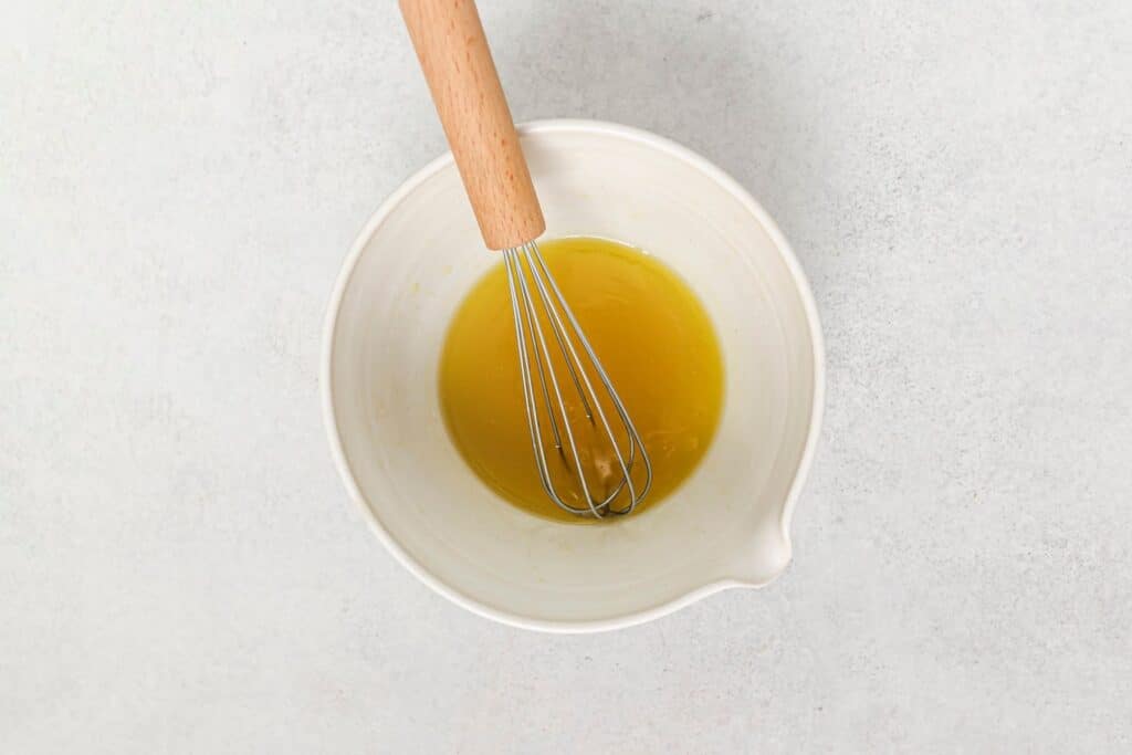 A bowl of homemade dressing with a whisk.