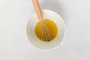 A bowl of homemade dressing with a whisk.