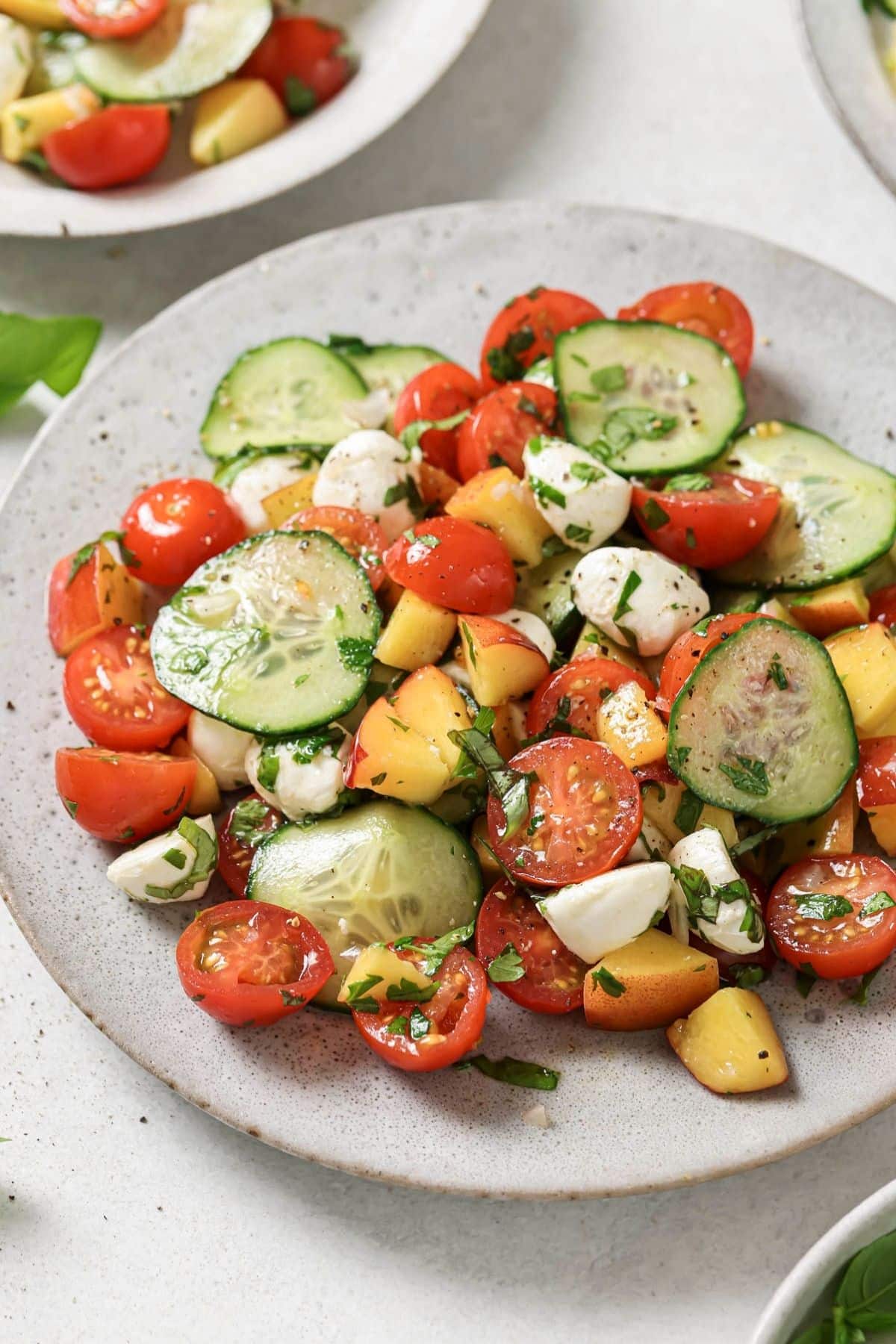 Cherry tomato salad on a gray plate with more salad in the background.