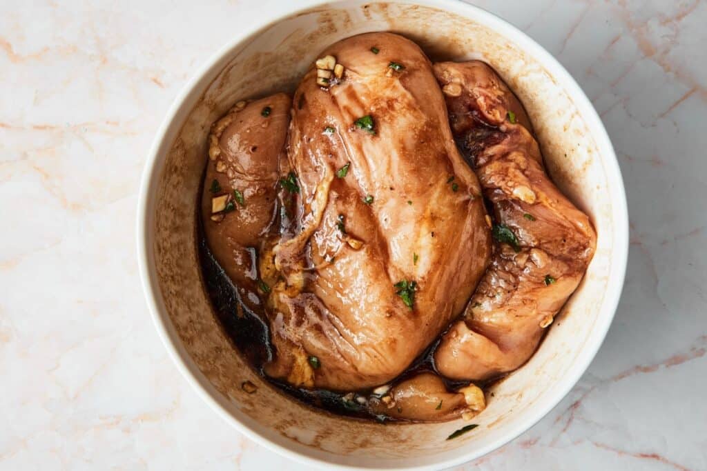 Chicken marinating in a bowl.