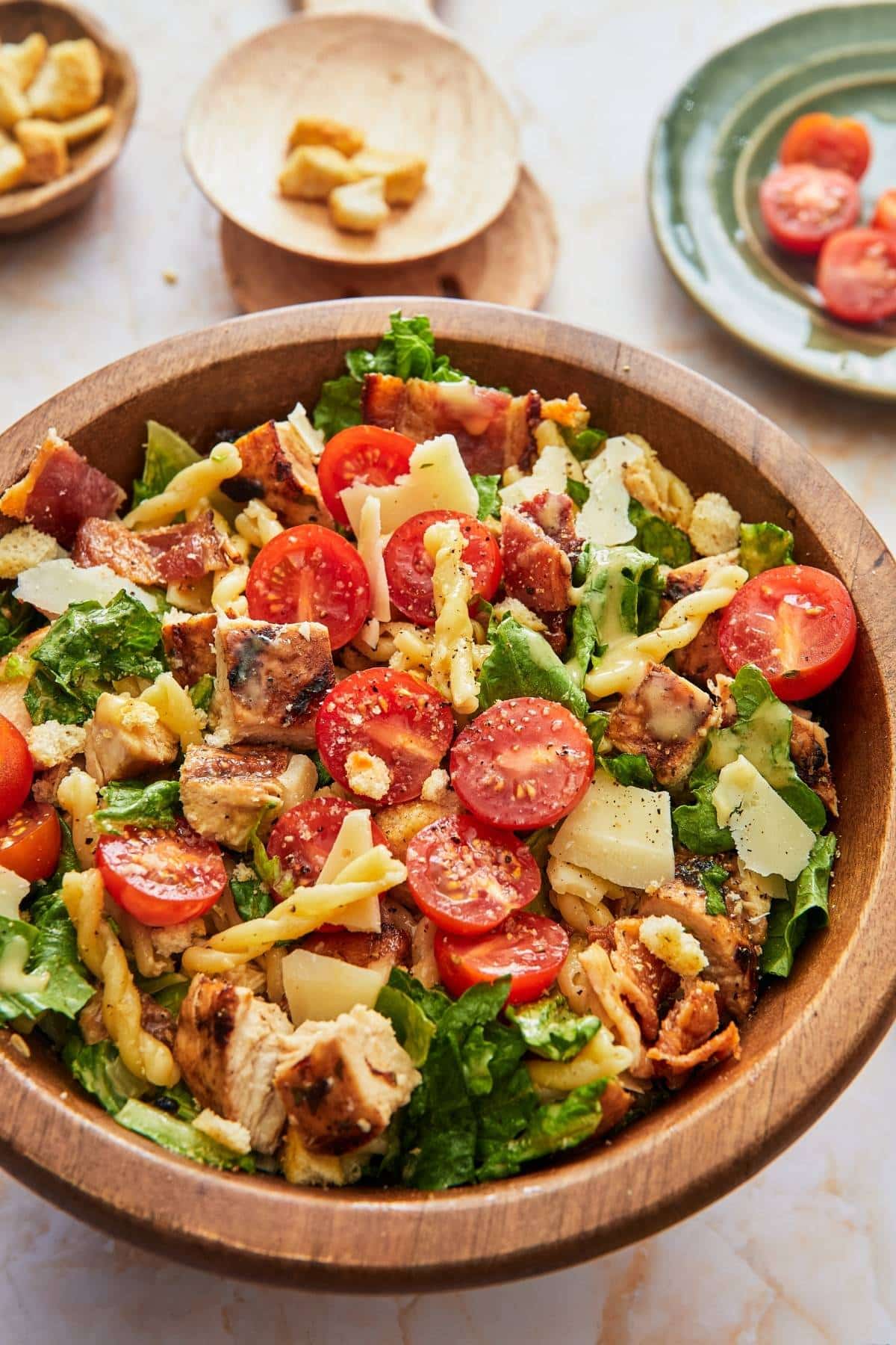 A wooden bowl full of caesar pasta salad.