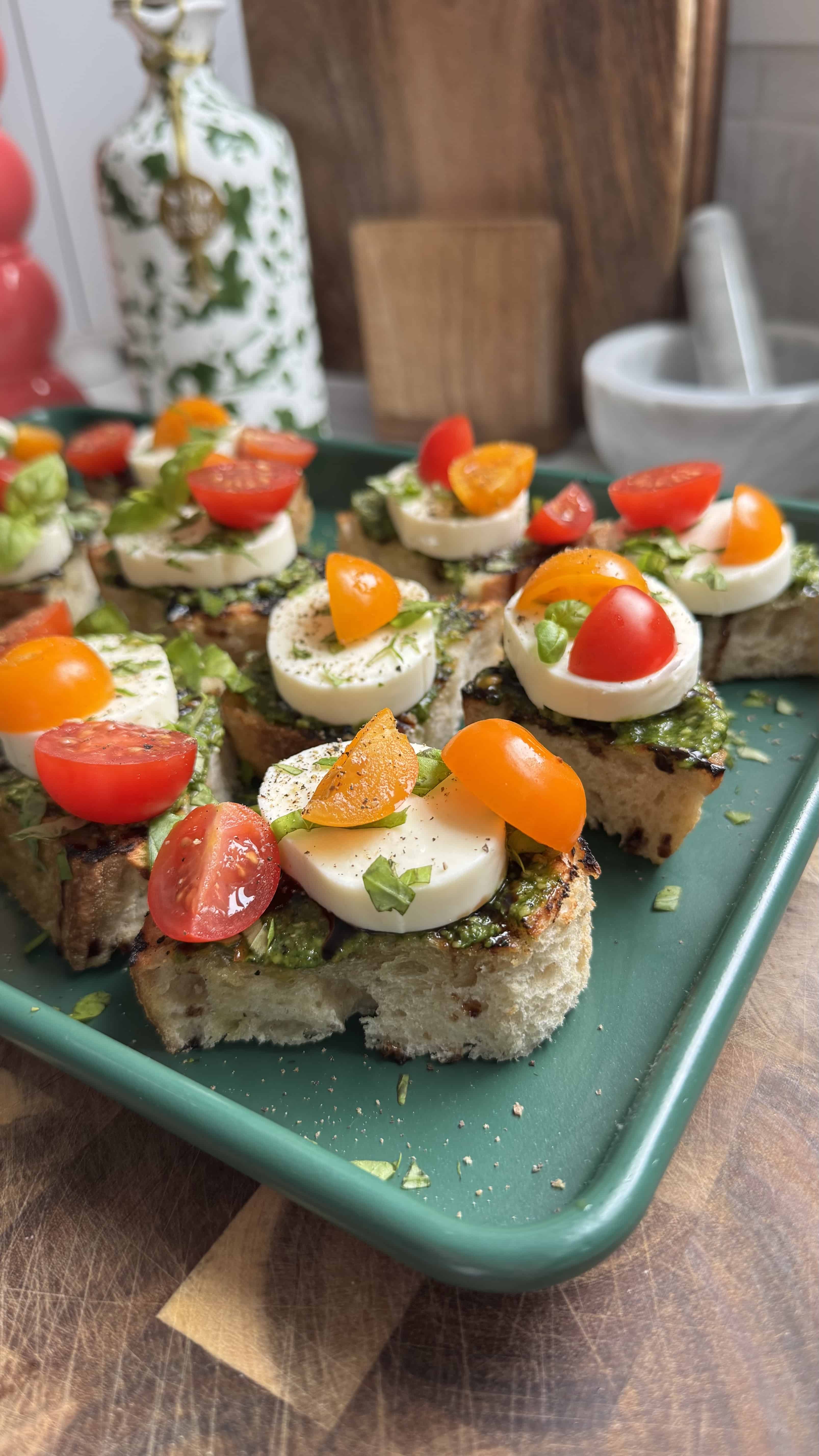 Tomato toast with mozzarella on a green sheet pan.