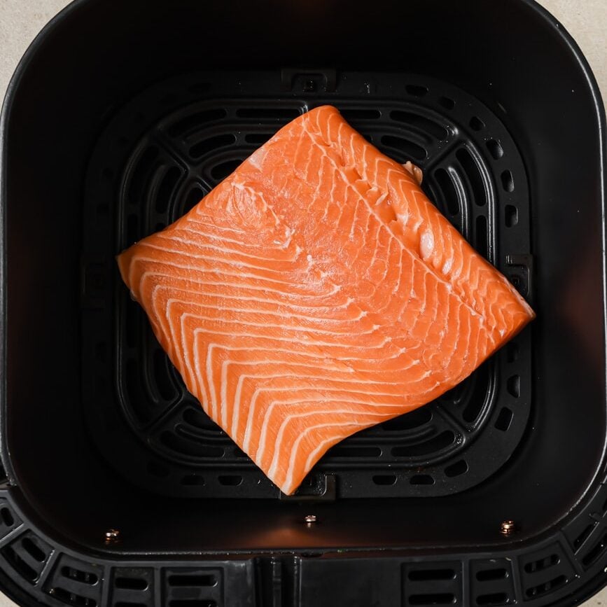 Salmon fillet in a black air fryer basket.