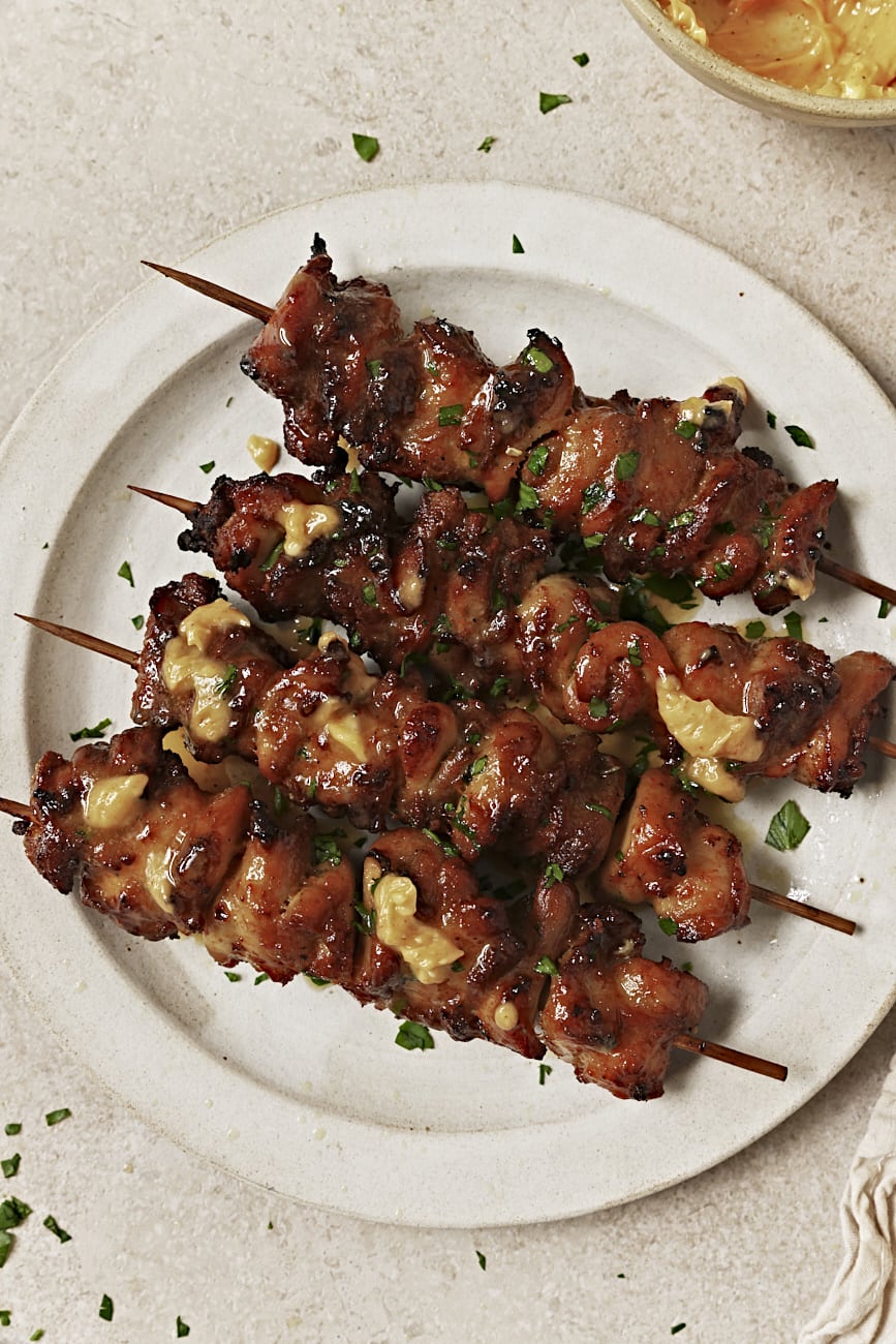 lemon butter chicken skewers on a white plate with lemon butter on top