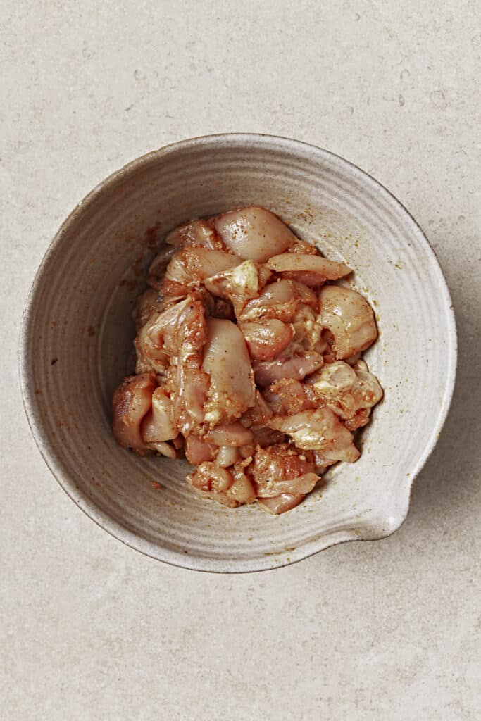 Raw chicken in a bowl with seasonings