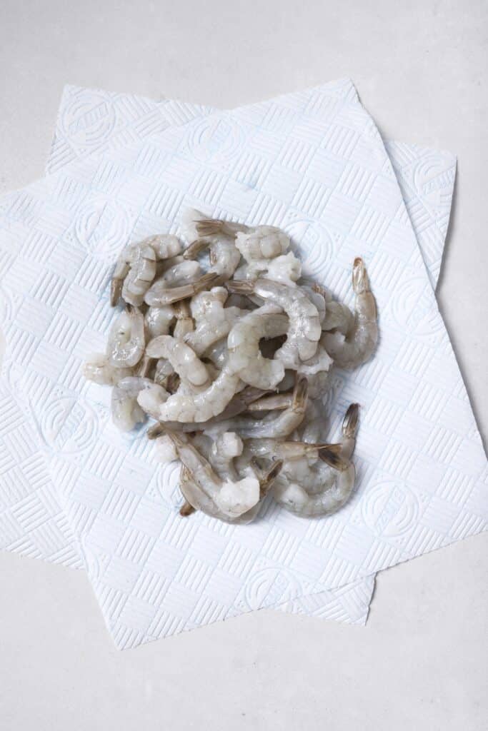 Patting shrimp dry with paper towels.