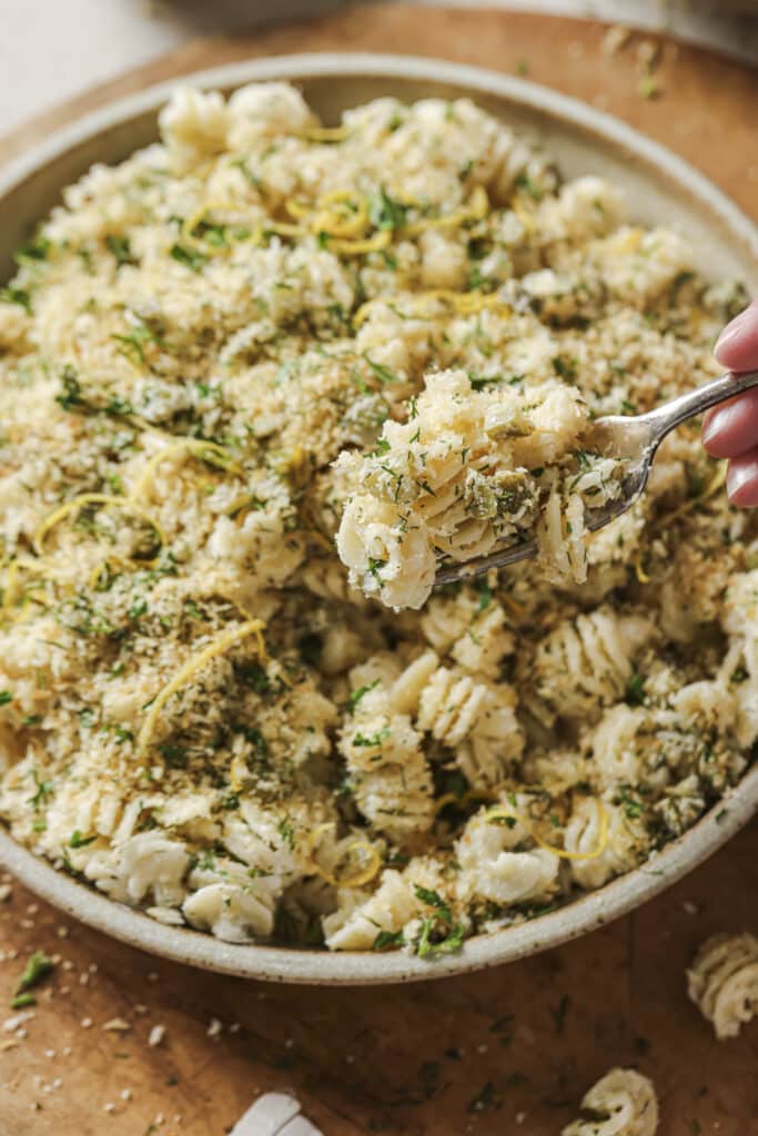Dipping into a fried pickle pasta salad with a fork.