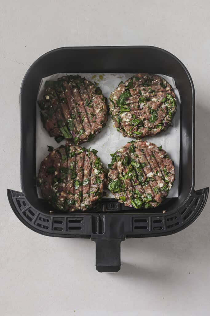 Uncooked turkey burgers in an air fryer.