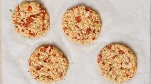 Four uncooked salmon patties on parchment paper.