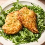 Two air fryer chicken cutlets on arugla.