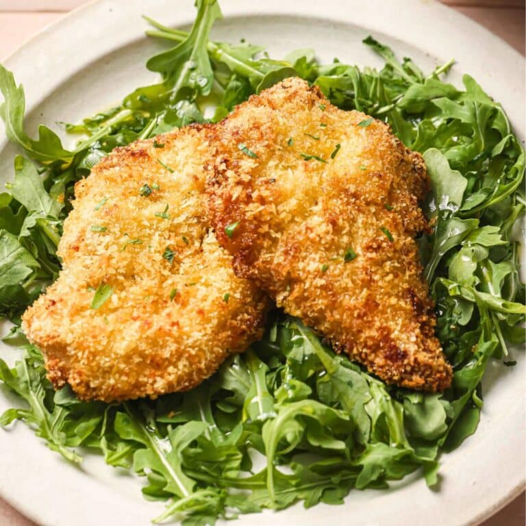 Two air fryer chicken cutlets on arugla.