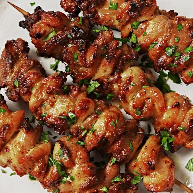 Air fryer chicken thighs skewered on a white plate.