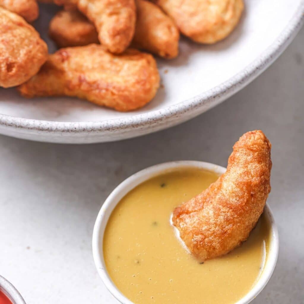 Dipping a chicken tender in honey mustard.