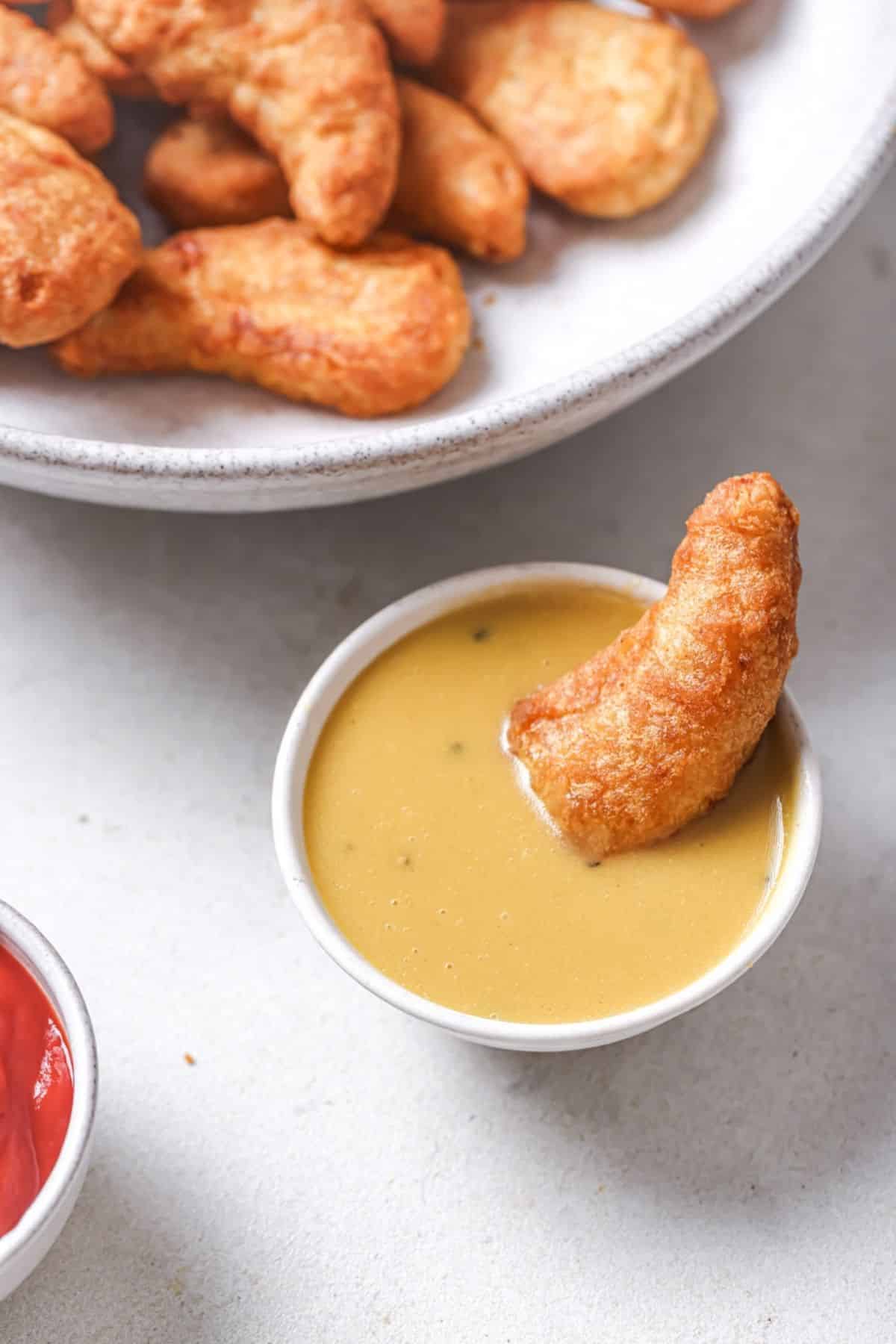 Dipping a chicken tender in honey mustard.