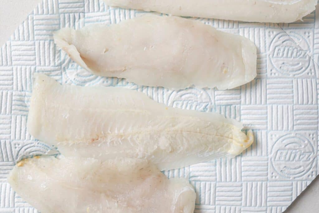 Preparing tilapia filets for seasoning.