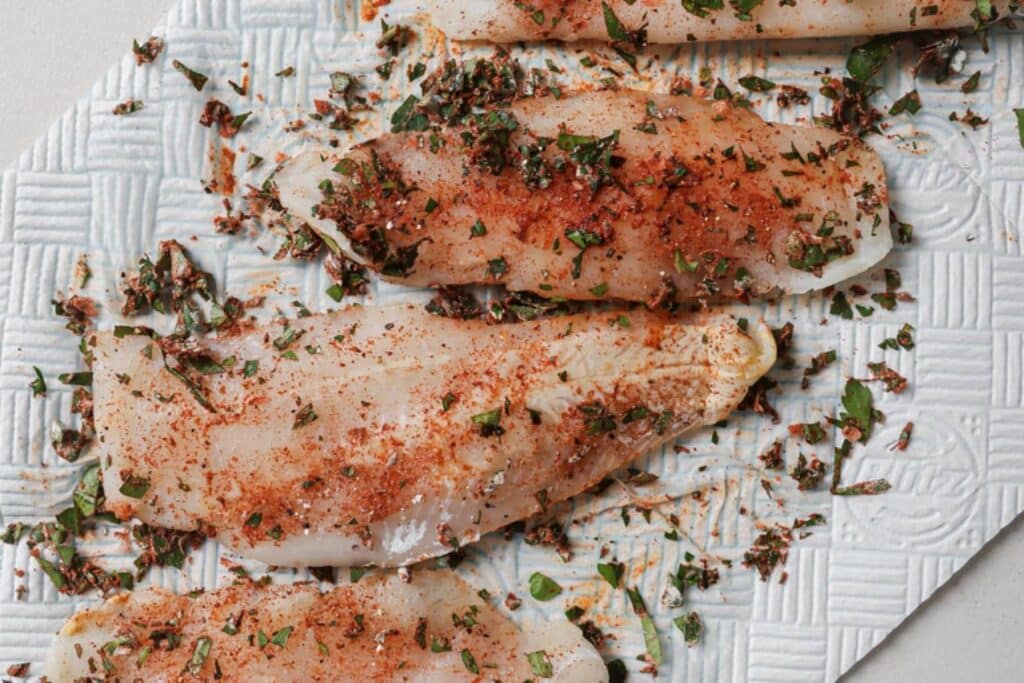 Seasoning tilapia filets.