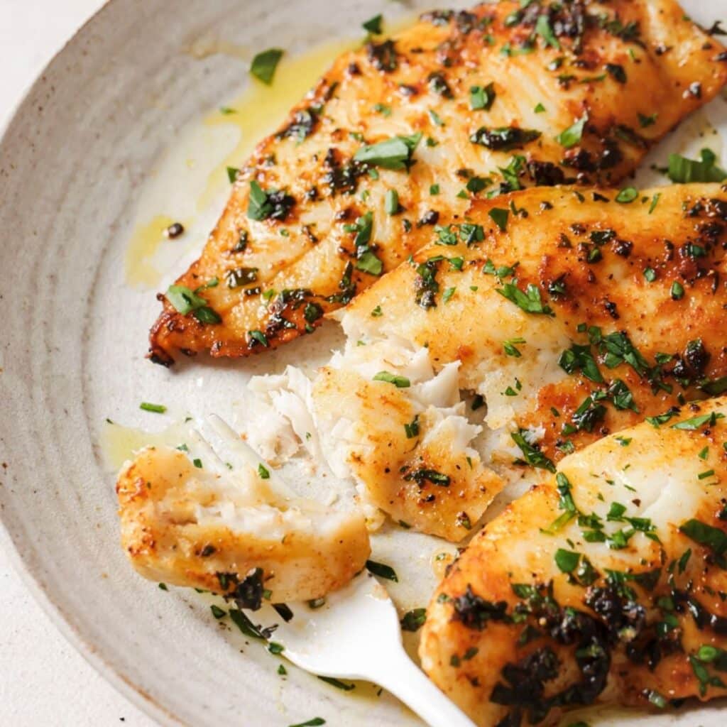 Taking a forkful of air fryer tilapia.
