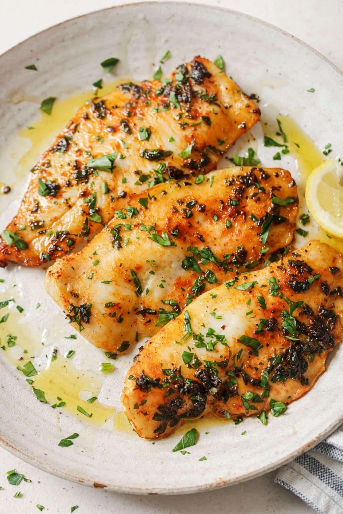 A plate of air fryer tilapia with a lemon wedge.