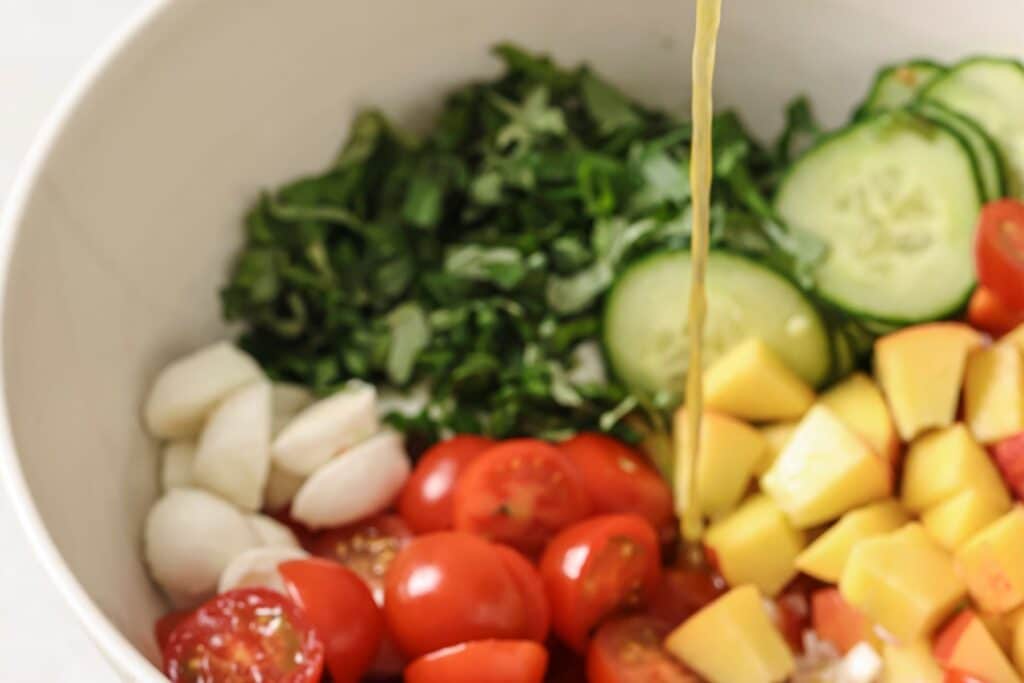 Pouring dressing over cherry tomato salad.